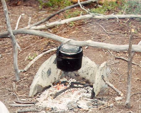 Pot with handle hanging over a campfire